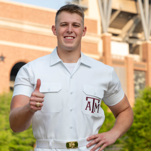Yell Leader Ethan giving a gig 'em and smiling at the camera.